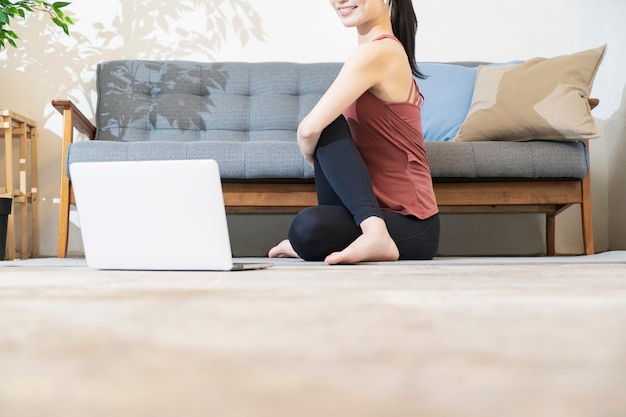 Une femme faisant du yoga tout en regardant l'écran de l'ordinateur dans la chambre