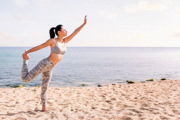 Photo une femme faisant de l'exercice sur la plage avec des poses de yoga