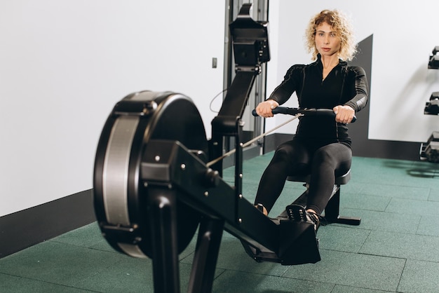 Photo femme faisant de l'exercice sur un rameur dans le cadre d'une séance de cardio d'échauffement en circuit