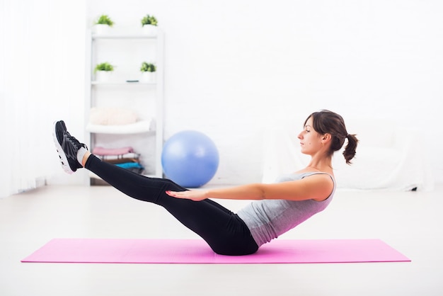 Femme faisant des exercices abdominaux sur tapis à la maison étirement pilates yoga fitness sport training