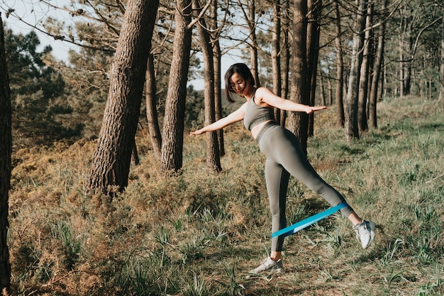 Femme faisant des exercices dans la forêt avec un élastique