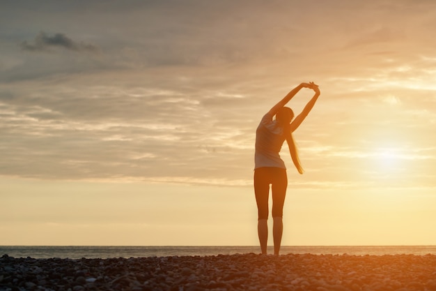 femme faisant des exercices du matin à la plage. Aube. Vue de dos