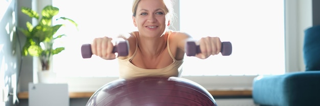 Femme faisant des exercices avec des haltères sur un ballon de sport