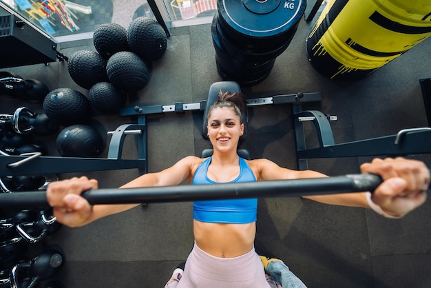 Femme faisant des exercices avec des haltères sur une formation de développé couché