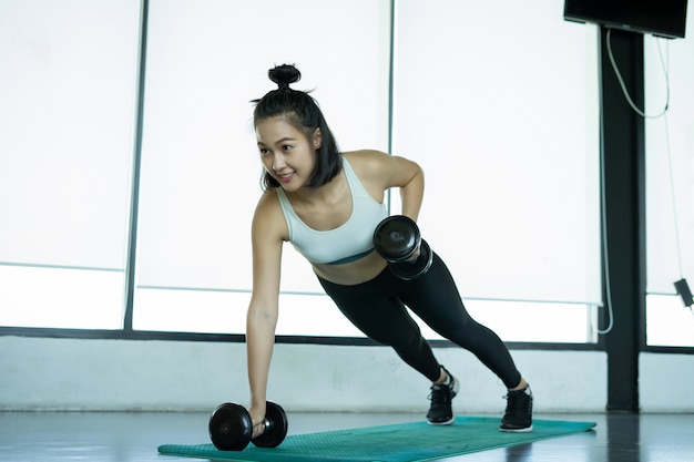 Femme faisant de la formation de fitness Femme fitness faisant des push ups sur un tapis d'entraînement. jeune femme faisant des tractions au gymnase. Femme musculaire faisant des pompes sur tapis d'exercice au gymnase.