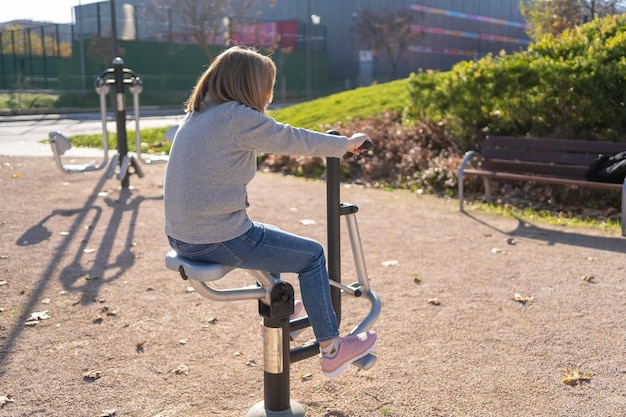 Femme faisant de la gymnastique sur un appareil public dans un parc de la ville pour s'entraîner et rester en bonne santé