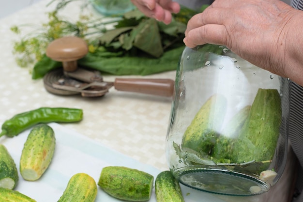 Femme faisant des légumes marinés dans un bocal en verre avec des herbes et des épices préparées pour la conservation Mise au point sélective Concept de préparations d'automne de récolte