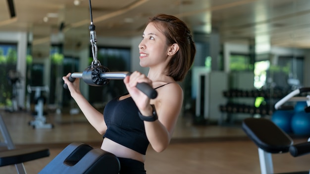 Photo femme faisant la machine à tirer lat dans la salle de sport