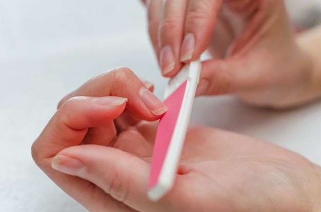 Femme faisant la manucure avec une lime à ongles. Concept de soins des ongles à domicile.