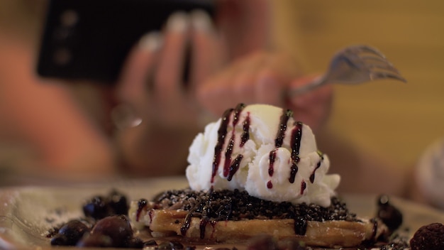 Femme faisant une photo mobile de dessert avec de la crème glacée