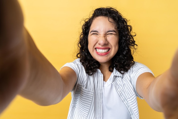 Femme faisant une photo de point de vue posant avec un sourire à pleines dents et les yeux fermés POV