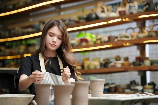 Femme faisant de la poterie dans l'atelier Façonner de l'argile humide sur un tour de potier