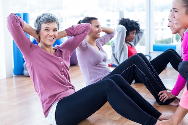 Femme faisant des redressements assis avec des amis au studio de remise en forme