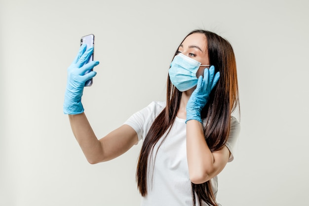 Femme faisant selfie portant masque et gants isolé sur fond blanc