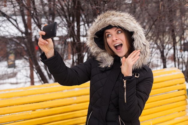 Femme faisant selfie avec smartphone debout dans le parc. L'hiver.