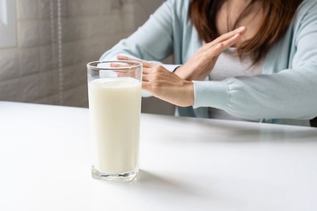 Femme faisant un signe X avec les mains croisées, faisant des gestes pour arrêter ou dire non pour boire du lait. Intolérance au lactose, concept d'allergie alimentaire.