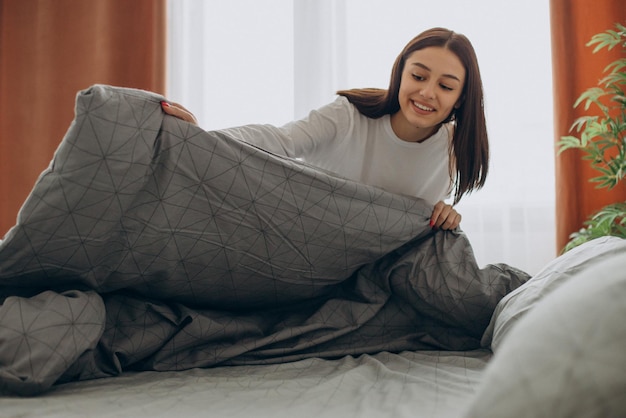 Femme faisant son lit après avoir dormi le matin