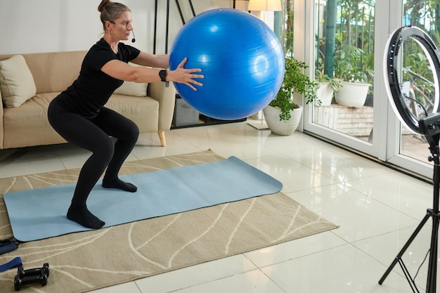 Femme faisant des squats avec ballon de fitness