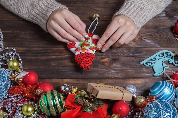 Femme fait des cadeaux de Noël sur une table en bois sombre.