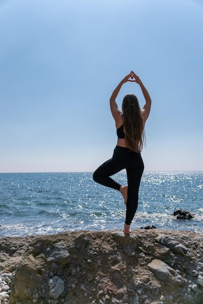 Femme fait coeur avec les mains sur la plage jeune femme avec instructeur de fitness cheveux longs qui s'étend