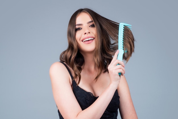 Une femme fait une coiffure avec un peigne belle jeune femme tenant un studio de cheveux sains et brillants