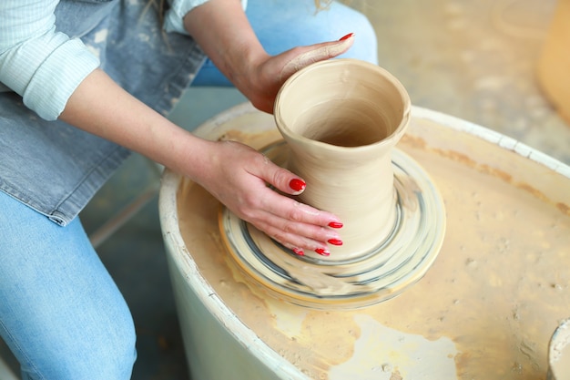 Femme fait une cruche de ses propres mains dans un atelier de poterie