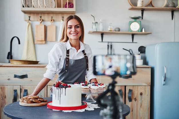 La femme fait de délicieux bonbons et tartes. Processus d'enregistrement par smartphone sur trépied.