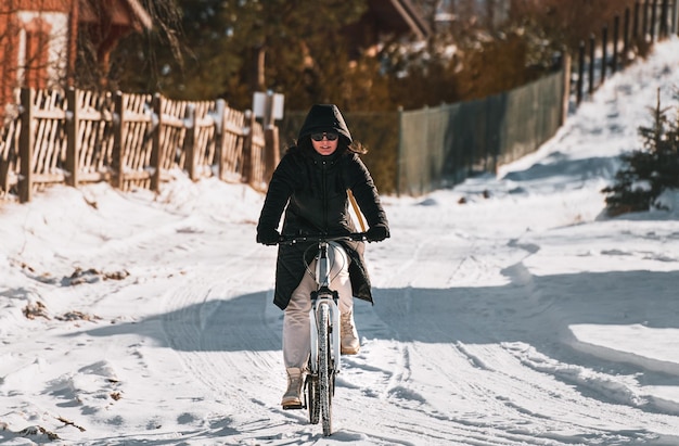 Une femme fait du vélo dans la neige de l'hiver