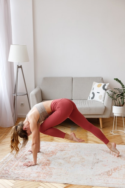 La femme fait du yoga dans le salon le matin