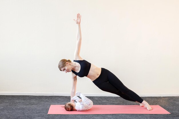 Une femme fait du yoga avec un enfant à la maison