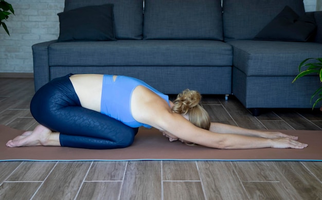 une femme fait du yoga à la maison