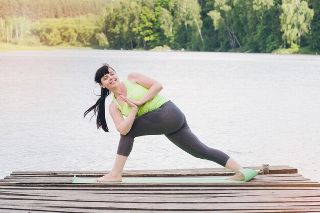 Femme fait du yoga sur le pont en été