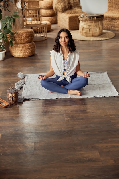 Femme fait du yoga et des pratiques méditatives dans une salle décorée de style bali