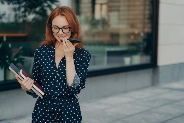 Une femme fait un enregistrement vocal en ligne pour envoyer des messages audio en extérieur