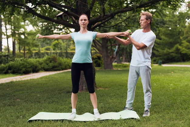 Femme fait des exercices avec des haltères. Un homme l'aide.