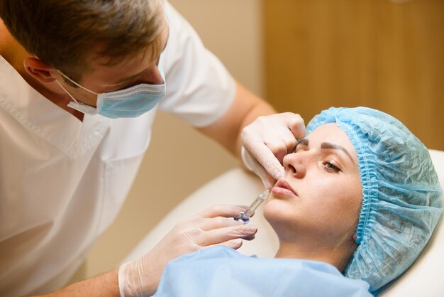 Une femme fait des injections faciales rajeunissantes pour l'augmentation des lèvres