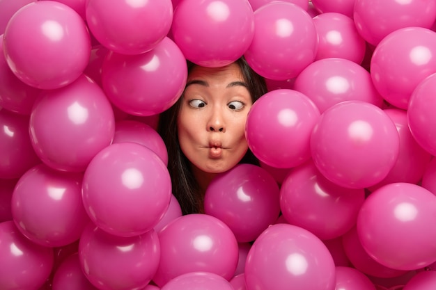 une femme fait des lèvres de poisson croise des yeux fous tout en décorant une salle avec des ballons gonflés