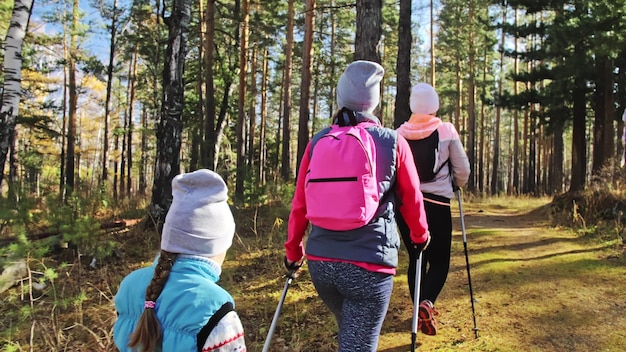 Une femme fait de la marche nordique dans la nature Les filles et les enfants utilisent des bâtons de trekking et des sacs à dos de bâtons nordiques