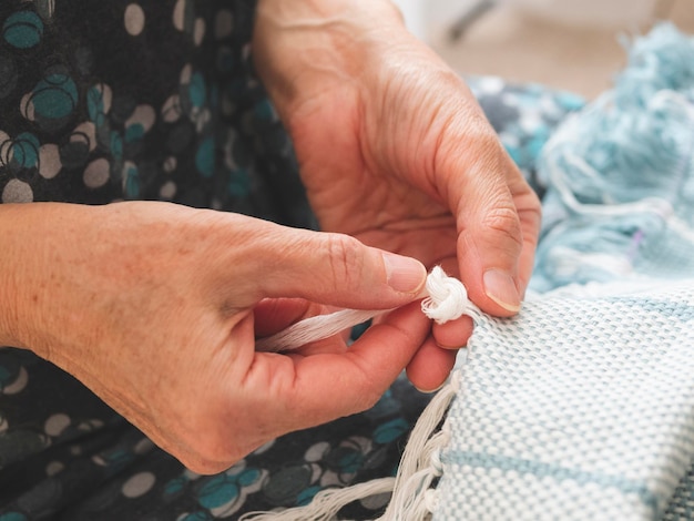 La femme fait des nœuds pour créer une frange sur un tissu Fini d'un tissage