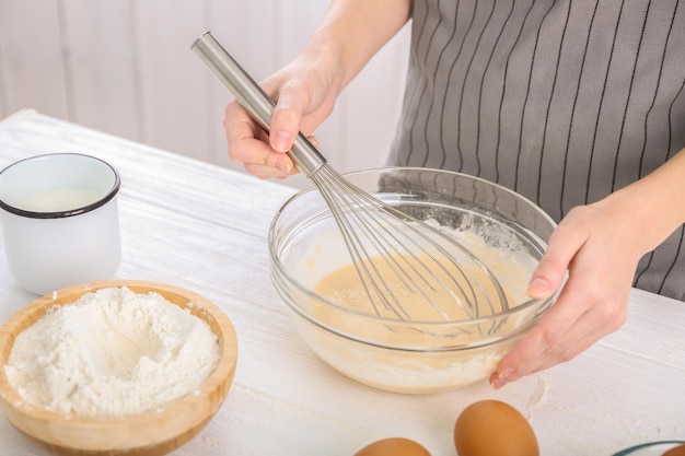 Une femme fait de la pâte sur la table de la cuisine