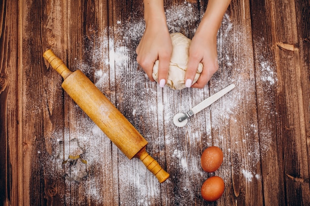 Femme fait des pâtisseries de Noël sur la pâte sur une table en bois