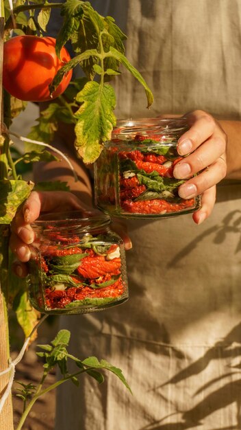 femme fait des préparations pour les tomates séchées d'hiver, l'ail haché et le basilic frais