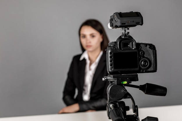 Une femme fait une vidéo pour son blog à l'aide d'un appareil photo numérique monté sur trépied