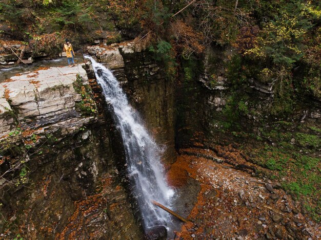 Femme sur la falaise regardant la cascade en profitant de la vue