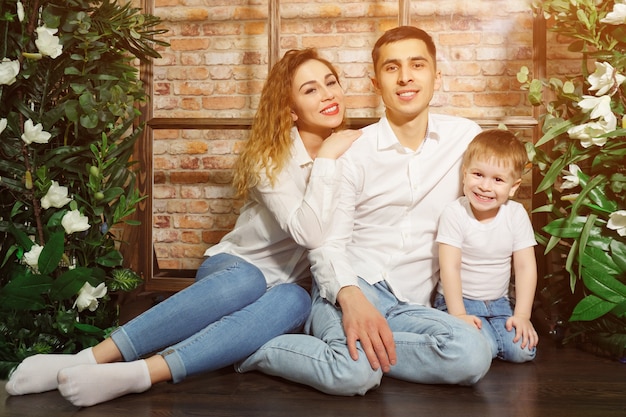 Une femme de famille heureuse et un homme avec un petit enfant regarde la caméra, la lumière du soleil