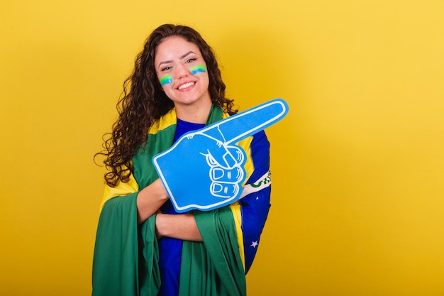 Femme fan de football fan de la coupe du monde du brésil portant des gants en mousse les bras croisés souriant confiant