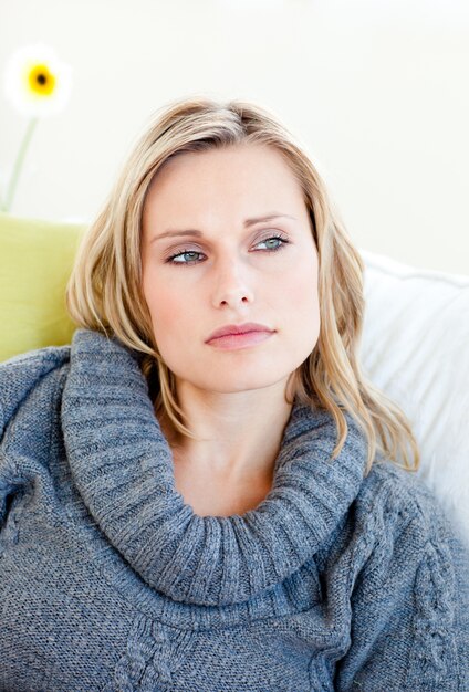 Femme fatiguée allongée sur le canapé avec un pull gris