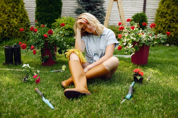 Photo femme fatiguée assise sur l'herbe dans le jardin