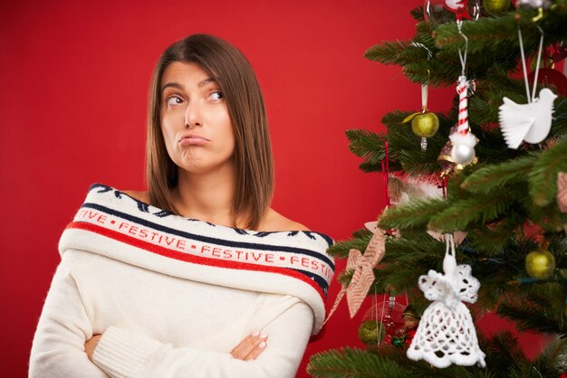 Femme fatiguée décorer l'arbre de Noël sur fond rouge