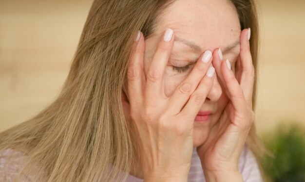 Une femme fatiguée dont le visage est couvert de mains Concept d'équilibre vie-travail